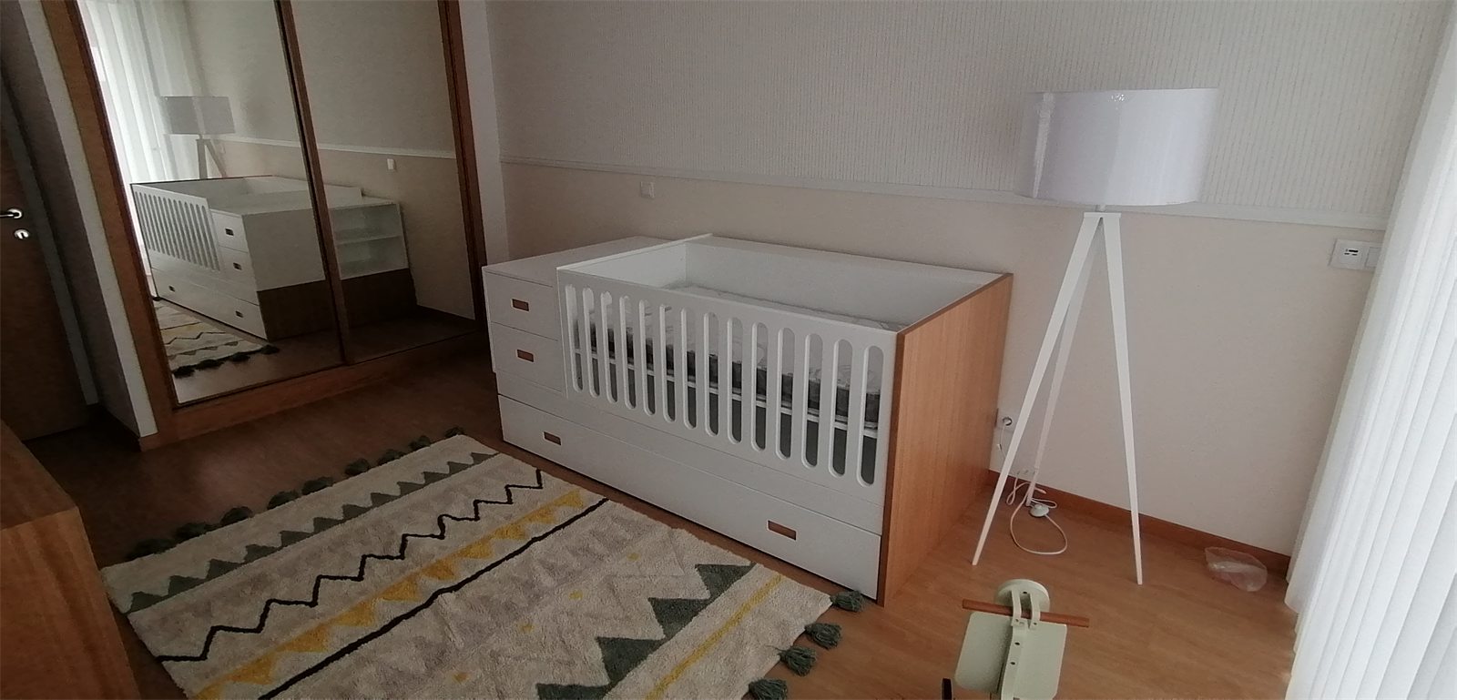 Habitación de bebé terminada con la cuna, la lámpara de trípode y la alfombra