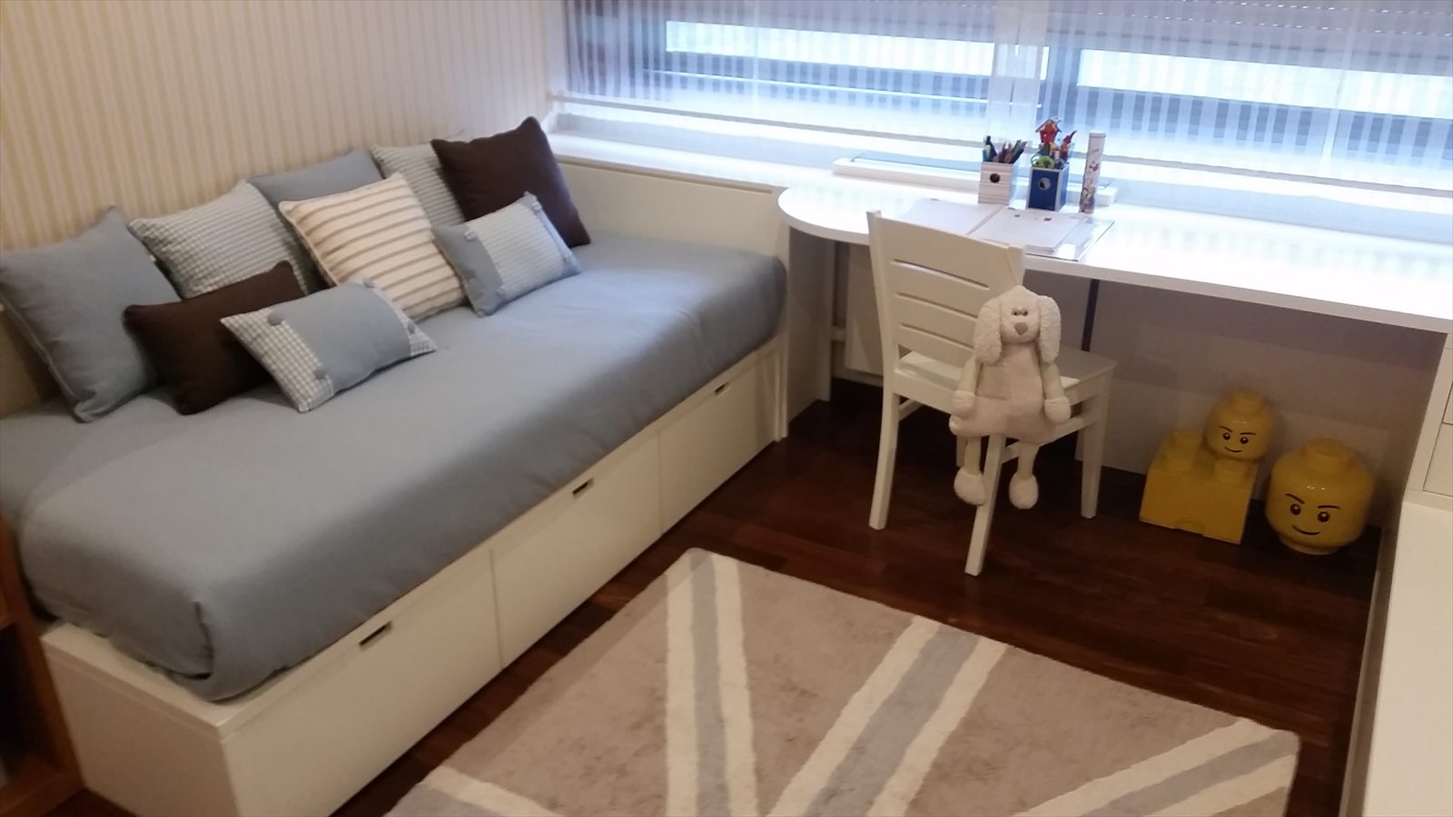 Habitación con cama de cajones y escritorio corrido bajo la ventana