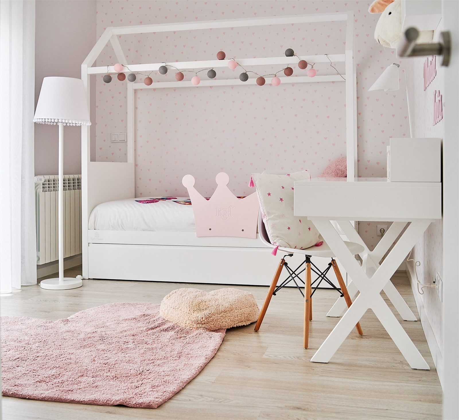 Habitación infantil con cama casita, cabecero corona en rosa y alfombra