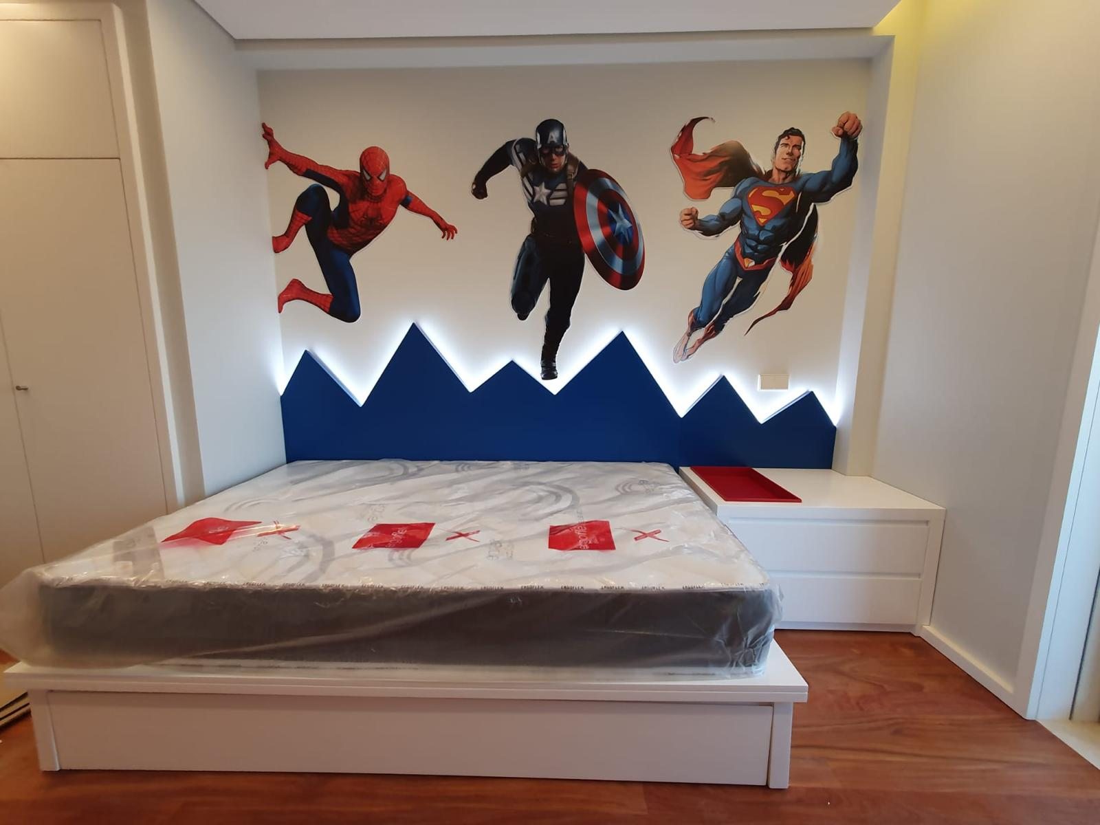 Cabecero con silueta de montaña retroiluminada y mural de superhéroes